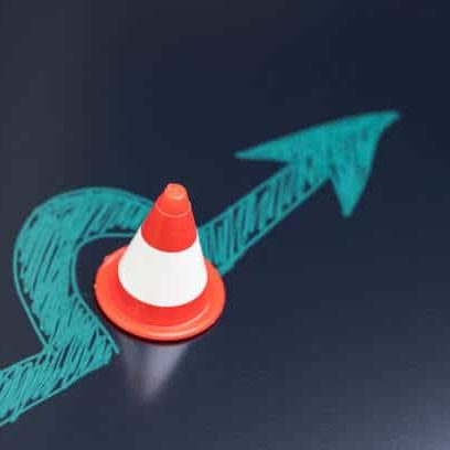Chalk drawing arrow turn or break through road block traffic pylon on dark blackboard using as obstacle, solution for business problem or break through to success concept.